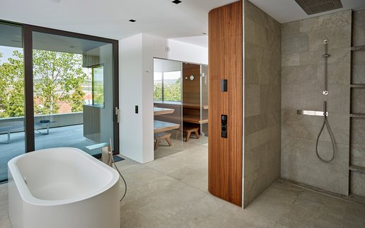 Privater Wellnessbereich: Aufeinander abgestimmte Materialien im gesamten Wellnessbereich: Neben der Sauna finden sich hier auch eine edle Regendusche und eine freistehende Badewanne.